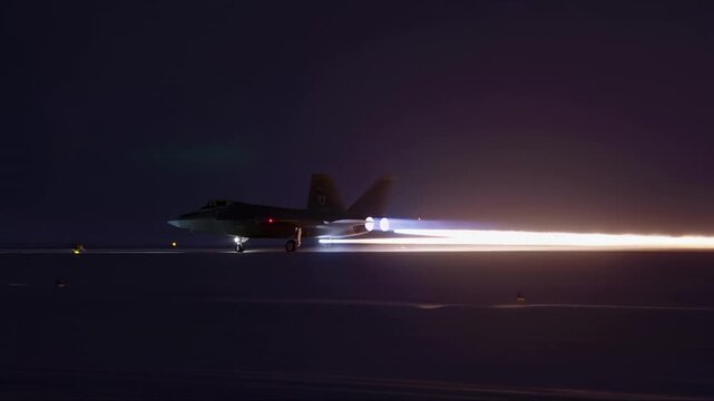 Fighter jet accelerating on runway at night with engine afterburners e