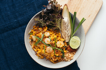 Overhead View of Shrimp Pad Thai in Gray Bowl with Lime and Herbs