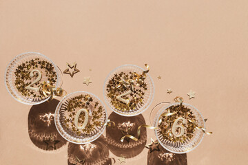 2026 Happy New Year glittering golden numbers in champagne glasses with festive party decoration top view.