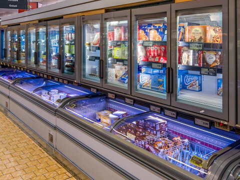 Italy - July 31, 2025: Various types and brands of packaged ice cream displayed on a counter and in a refrigerated display case for sale at an Italian Lidl discount store.