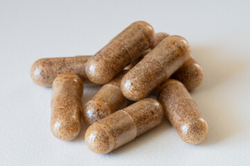 Pile of herbal capsule with brown powder isolated on white