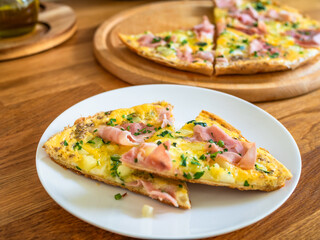 Frittata - scrambled eggs with zucchini and boiled ham on wooden table	