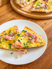 Frittata - scrambled eggs with zucchini and boiled ham on wooden table	