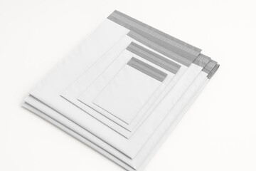 Set of white and gray poly mailer bags in multiple sizes, stacked neatly on a clean white background, ideal for secure shipping and e-commerce packaging