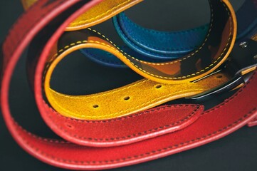 Leather belts on a black background. Abstract, artistic mosaic of belts. Twisted handmade belts made of patterned leather. Blurred image