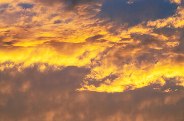 Warm sunset sky glowing with vibrant orange clouds and contrasting dark gray shadows spreading wide