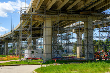 Looking up under a bridge that is under repair. Much steel scaffolding is under the bridge.