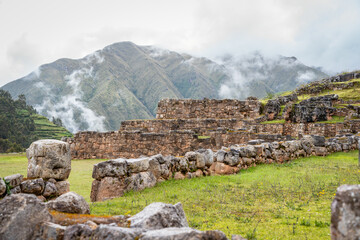 Ancient Inca stone terraces at the archaeological site of Chinchero, Peru against misty Andean mountains