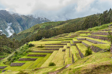 Ancient Inca stone terraces at the archaeological site of Chinchero, Peru against misty Andean mountains