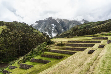 Ancient Inca stone terraces at the archaeological site of Chinchero, Peru against misty Andean mountains