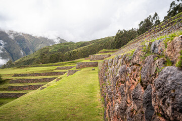 Ancient Inca stone terraces at the archaeological site of Chinchero, Peru against misty Andean mountains
