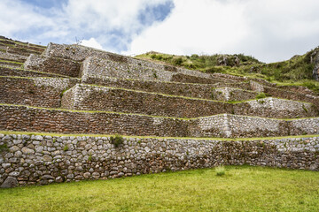 Ancient Inca stone terraces at the archaeological site of Chinchero, Peru against misty Andean mountains