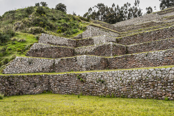 Ancient Inca stone terraces at the archaeological site of Chinchero, Peru against misty Andean mountains