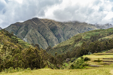 Scenic landscape with lush green terraces and misty Andean mountains at the Archaeological Site of Chinchero, Peru