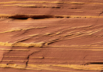 Naklejka premium A close-up, detailed texture of a layered red sandstone rock formation, showing natural lines and a rough, sandy surface.