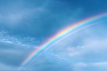 A vibrant rainbow arches across a cloudy blue sky, a symbol of hope and wonder
