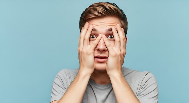 Stressed Young Man with Hands on Face Expressing Anxiety and Distress in a Light Blue Background, Capturing Emotional Turmoil and Modern Life Pressures for Mental Health Awareness Campaigns
