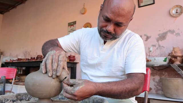 Afro-Brazilian man, third generation of a family of potters, crafting clay pieces inspired by ancient Tapajonic art to preserve cultural tradition in Santarem, Para, Brazil