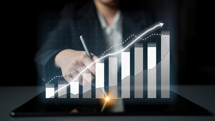 A businessperson analyzes financial data using a modern tablet displaying digital graphs and charts, emphasizing growth and strategy in a professional environment. Impute