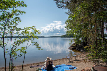 Woman sitting on the beach at lake Saimaa in Finland