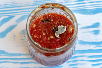 This is an image of a jar filled with a red sauce which appears to be a type of salsa or chutney