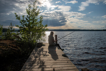 Woman sitting on the pier and fishing