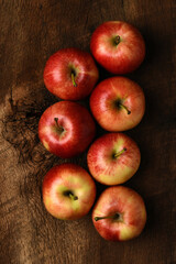 A group of fresh picked Gala Apples on a rustic wood table. Two rows of apples shot from directly above.