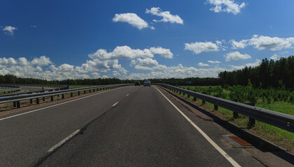 Naklejka premium Road view on a summer day. Highways and cars, roadside and white road line markings.