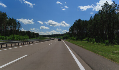 Road view on a summer day. Highways and cars, roadside and white road line markings.