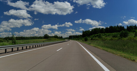 Fototapeta premium Road view on a summer day. Highways and cars, roadside and white road line markings.