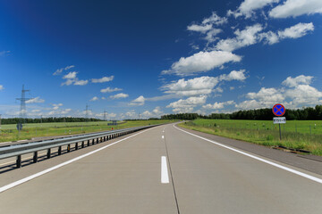 Fototapeta premium Road view on a summer day. Highways and cars, roadside and white road line markings.