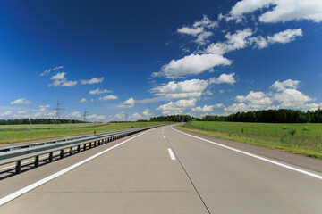 Fototapeta premium Road view on a summer day. Highways and cars, roadside and white road line markings.