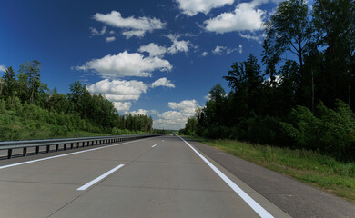 Fototapeta premium Road view on a summer day. Highways and cars, roadside and white road line markings.