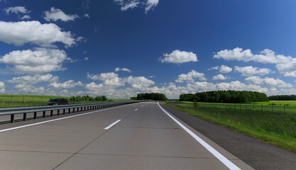 Fototapeta premium Road view on a summer day. Highways and cars, roadside and white road line markings.