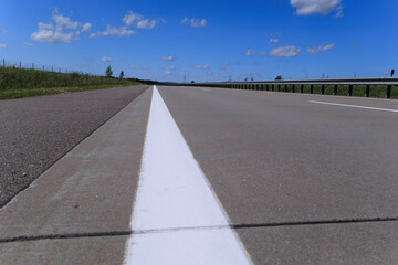 Road view on a summer day. Highways and cars, roadside and white road line markings.