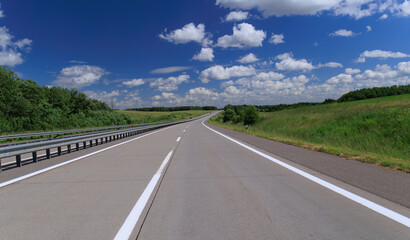 Road view on a summer day. Highways and cars, roadside and white road line markings.