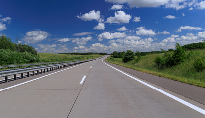 Road view on a summer day. Highways and cars, roadside and white road line markings.