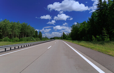 Road view on a summer day. Highways and cars, roadside and white road line markings.