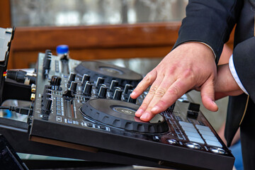 A person's hands operating a DJ mixing console