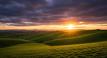 Fototapeta premium Rolling green hills under dramatic cloudy sky at golden hour