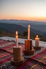 Three lit candles on a patterned blanket at sunset