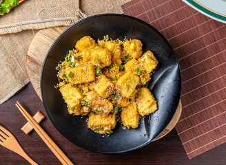 Crispy Fried Tofu with Sesame Seeds and Scallions in Black Bowl, Delicious Asian Vegan Appetizer Dish Side view