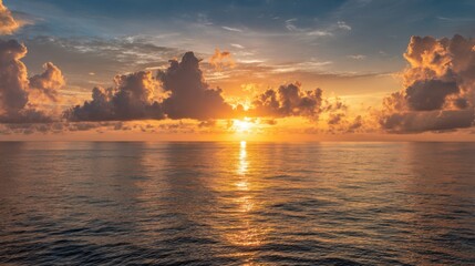 Fototapeta premium The sun is setting over the ocean, casting a warm glow on the water. The sky is filled with clouds, creating a serene and peaceful atmosphere