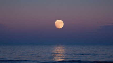 A large moon is shining on the water. The sky is a beautiful shade of purple. The scene is peaceful and serene
