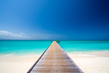 Obraz premium A long wooden pier extends out to the bright turquoise ocean under a clear blue sky, leading towards the horizon.