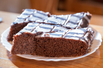 A brown chocolate cake with icing on a white plate.
