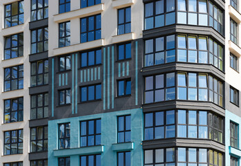 Closeup of modern highrise building facade. Multiple glass windows and balconies create geometric