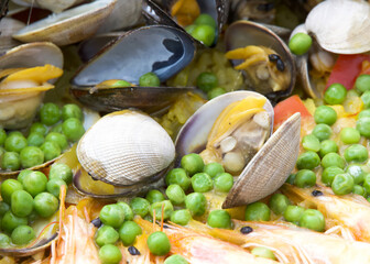 Close up on clams, muscles, shrimp rice and peas cooking in a giant outdoor wok. Mexican seafood dish called Paella