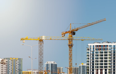 Construction cranes over tall high rise tower with steel framework and concrete structure in