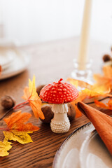 Autumn table setting with decorative mushroom and colorful leaves during fall season